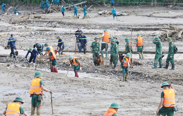 Hàng trăm cán bộ, chiến sĩ Công an, Quân đội dầm mình bới từng gốc cây, lật từng tảng đá tìm kiếm nạn nhân mất tích trong trận lũ quét ở Làng Nủ. (Ảnh: Báo Công an nhân dân)