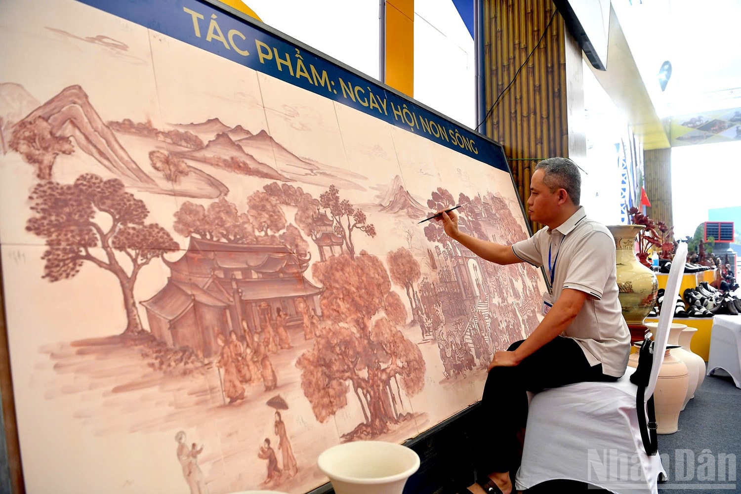 Nghệ nhân Gốm Chu Đậu trực vẽ gốm tại triển lãm, tạo sự hứng thú cho khách tham quan. ndo_br_anh-1-gom.jpg