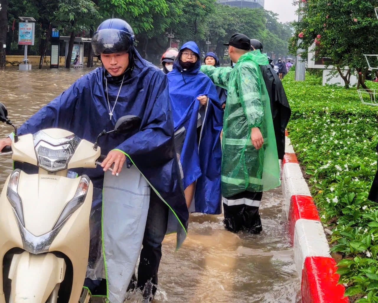 Người dân xếp hàng dắt xe đi qua khu vực nước sâu dưới sự hướng dẫn của Cảnh sát Cơ động Hà Nội. (Ảnh: QUỲNH LAN) z7090255366299-c4d1ee3d421e3f759a7779c586609471.jpg