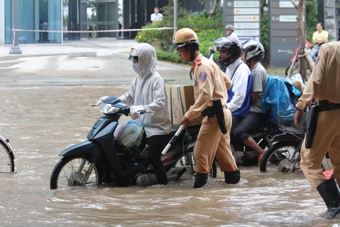 Cảnh sát giao thông Hà Nội hỗ trợ người dân vượt qua đoạn đường ngập. cs3-giaoducvietnam.jpg
