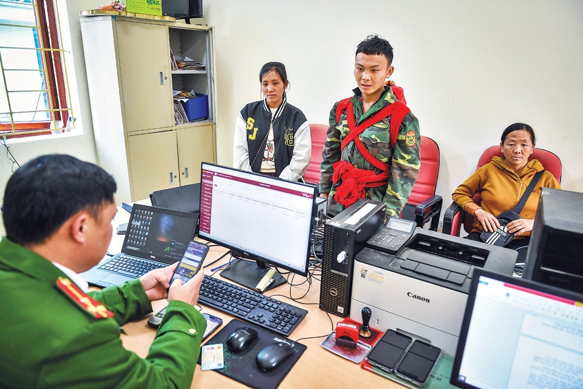 Cán bộ chiến sĩ công an hỗ trợ cài đặt VNeID cho người dân. (Ảnh: THÀNH ĐẠT) dat-0143.jpg